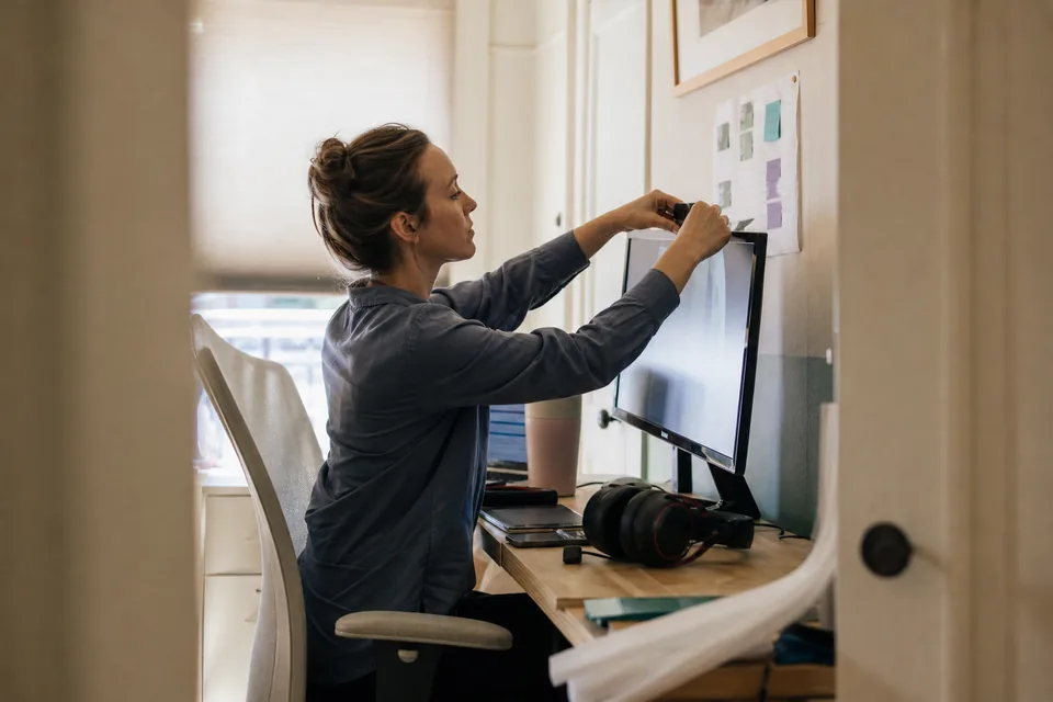Assistant setting up her home workspace with a webcam, headset and a printed weekly schedule